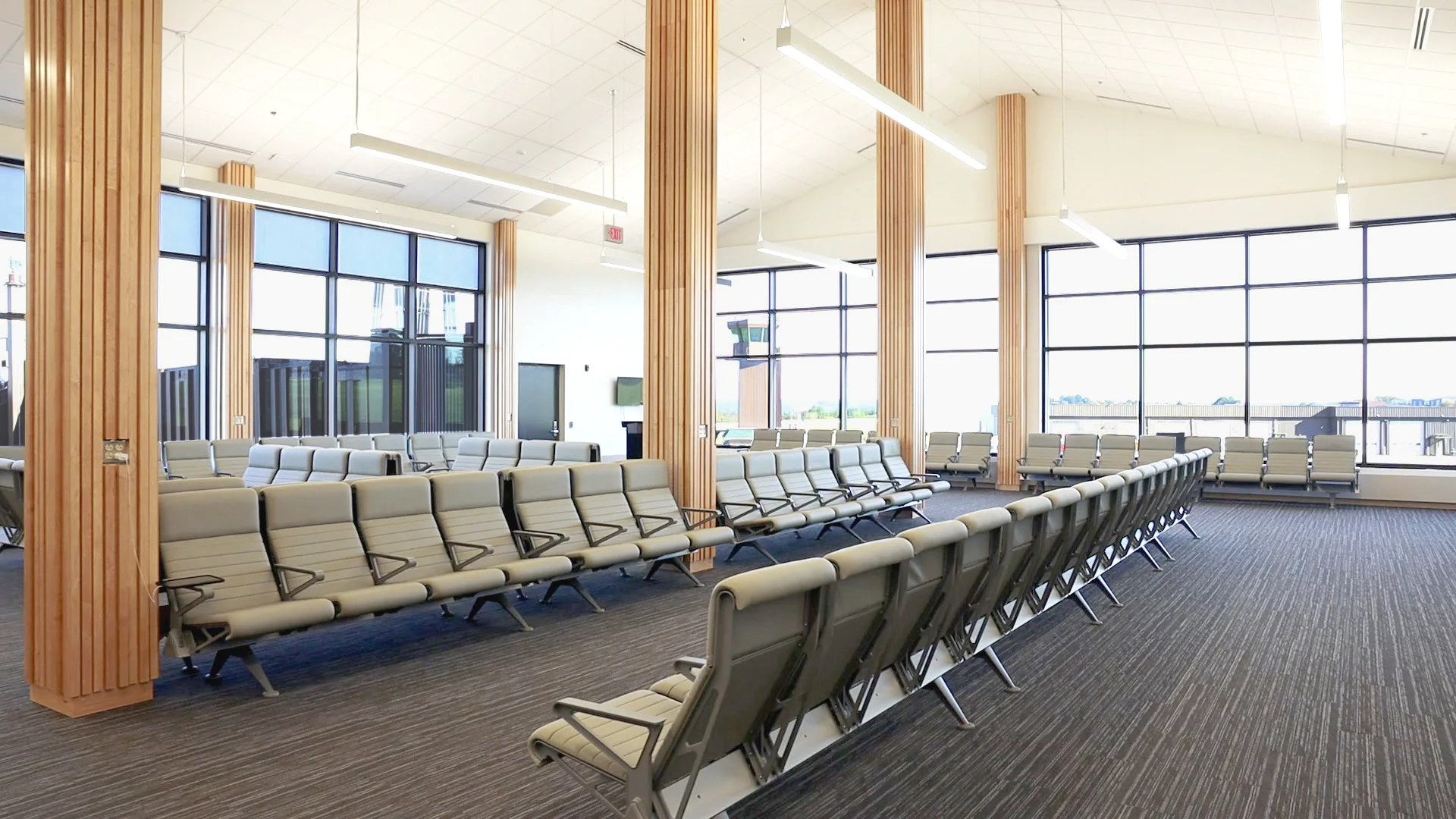 The new gate area at Arnold Palmer Regional Airport, with rows of seating, wood columns, and floor-to-ceiling windows
